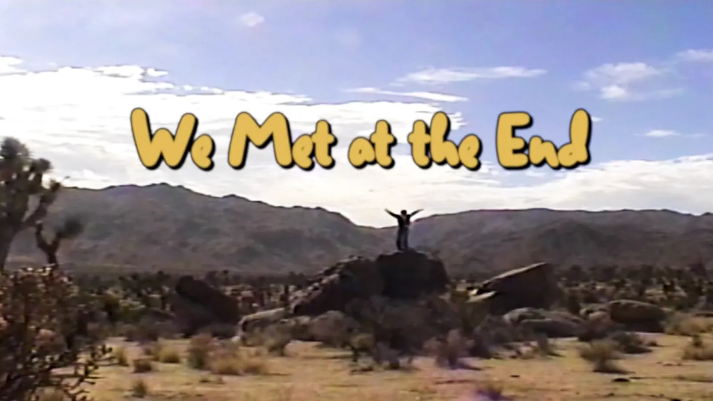 A lone figure in a desert landscape beneath the title We Met at the End